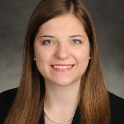Professional headshot of a smiling woman with long brown hair.